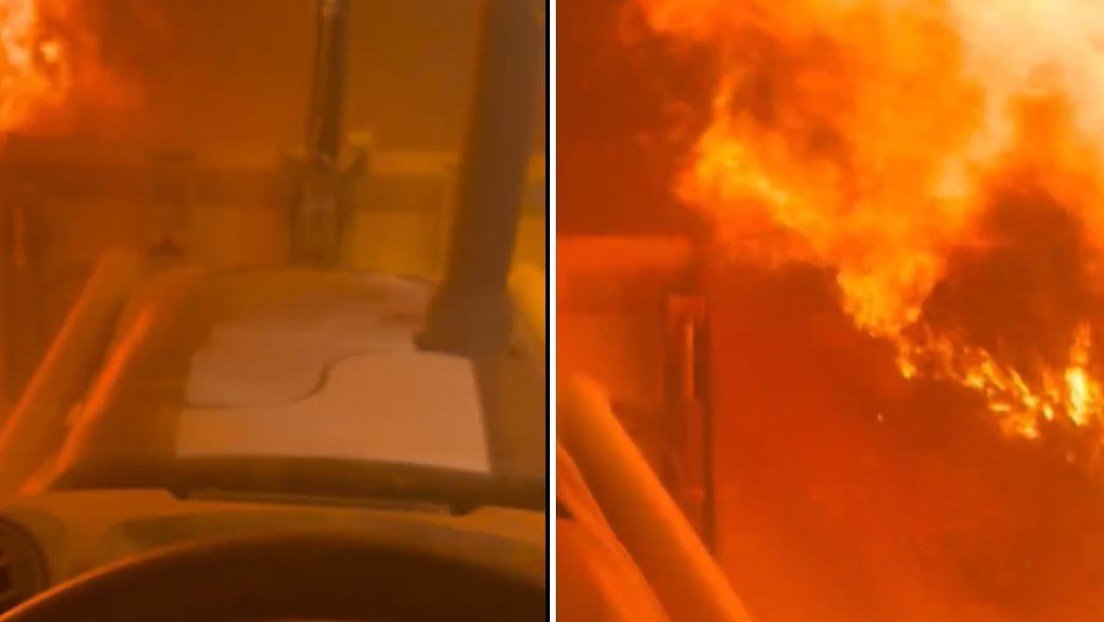 Operador conduce entre humo y fuego para contener un incendio que amenaza viviendas